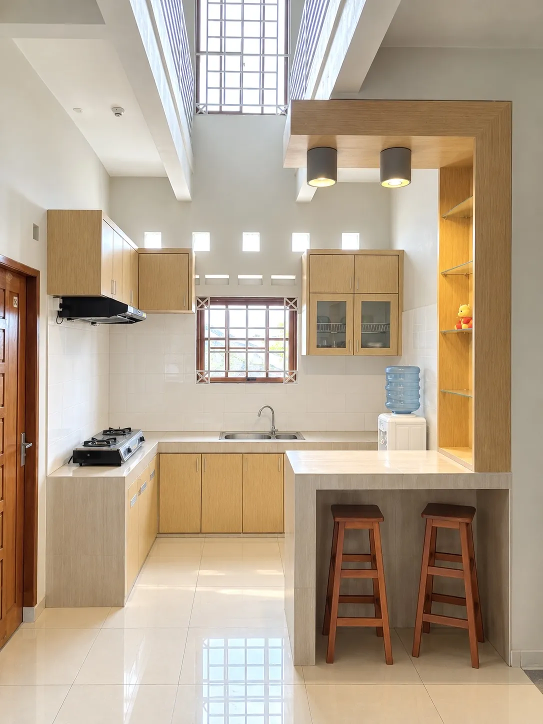 Shared kitchen with a stove, sink, a bar counter with stools and a water dispenser
